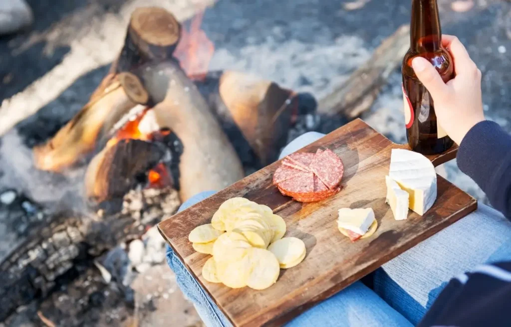 A platter of deli meats and cheeses being served by a campfire after transporting the snacks in a high-quality powered cooler.