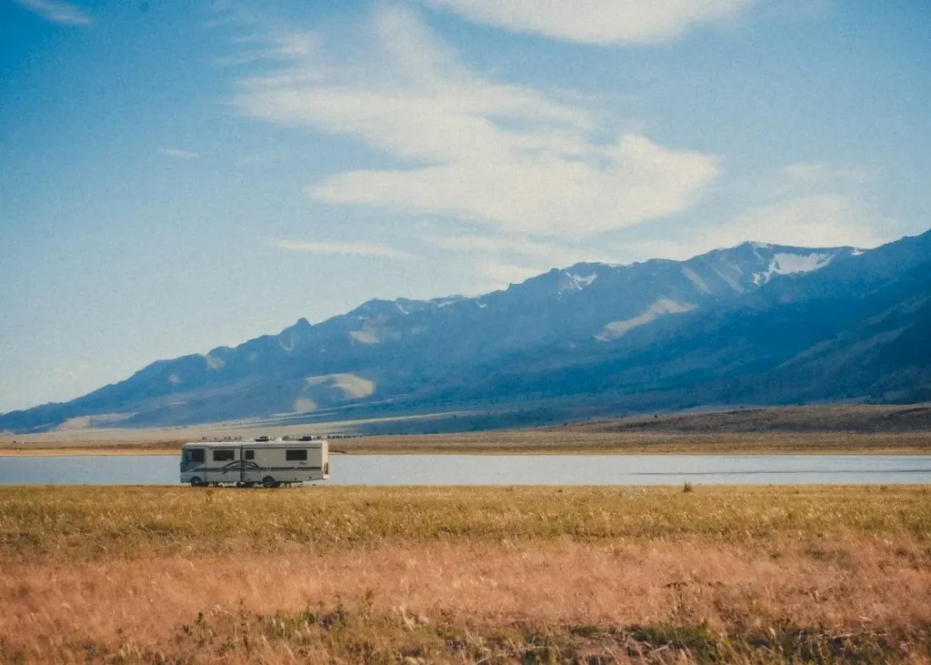 One of the smallest Class A RVs camped in a beautiful alpine landscape near a mountain and lake.