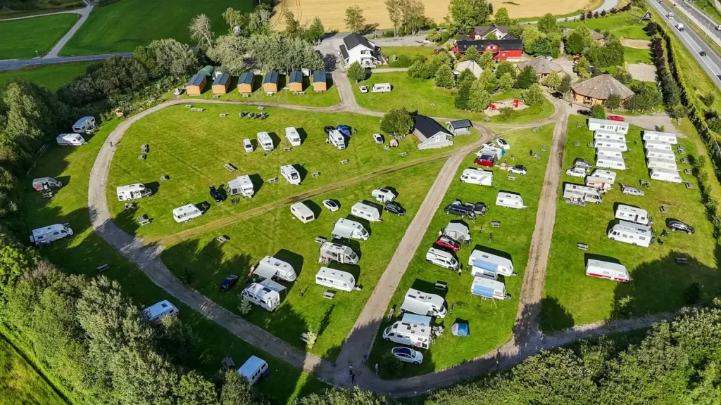 A more established campground for RVs featuring an array of motorhomes dry camping in a field at designated sites (as photographed from a drone).