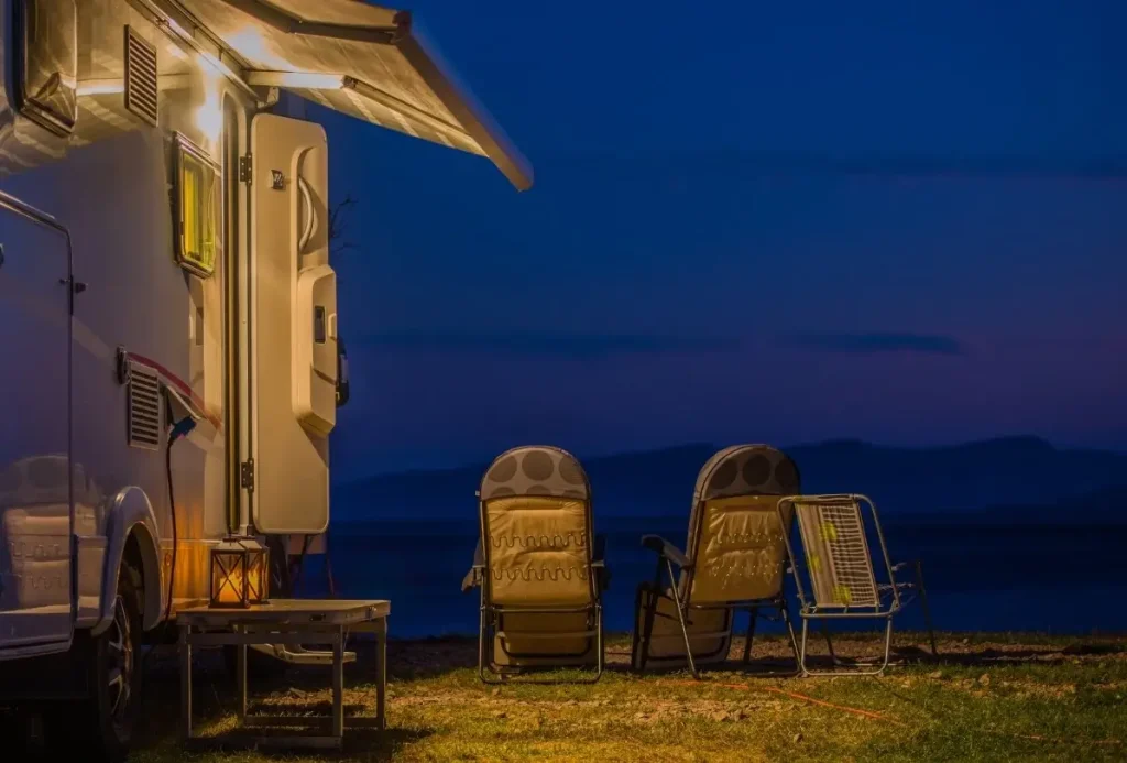 An RV parked on private property with the camp of a family of full-time RVers set up and overlooking mountains in the distance.