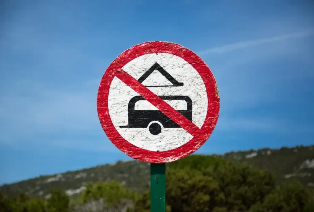 A 'No Camping' sign with a tent and RV crossed out to deter full-time and traveling RVers.