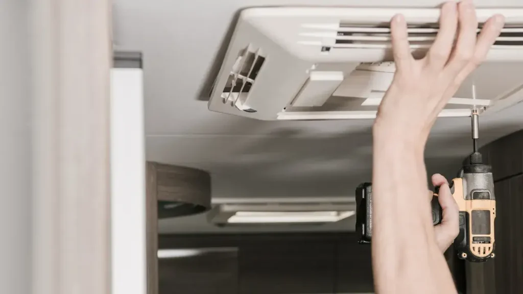 The hand of a man installing one of the best 12V RV air conditioners in his motorhome.