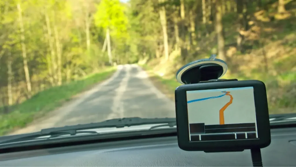 Someone driving an RV down a long forest road with one of the best RV GPS units attached to their windshield for mapping.