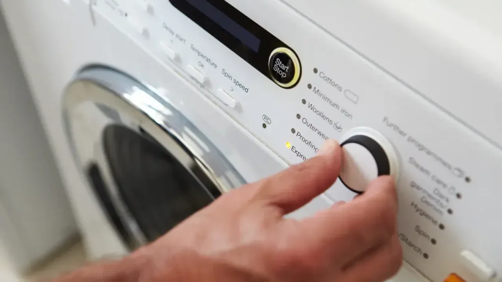 An RVer adjusting the settings on their top-of-the-line washer dyer combo inside their motorhome.