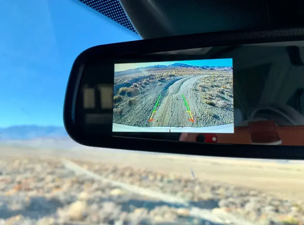 A close-up of the real-time display of one of the best RV bckup cameras in use on an unsealed, desert road.