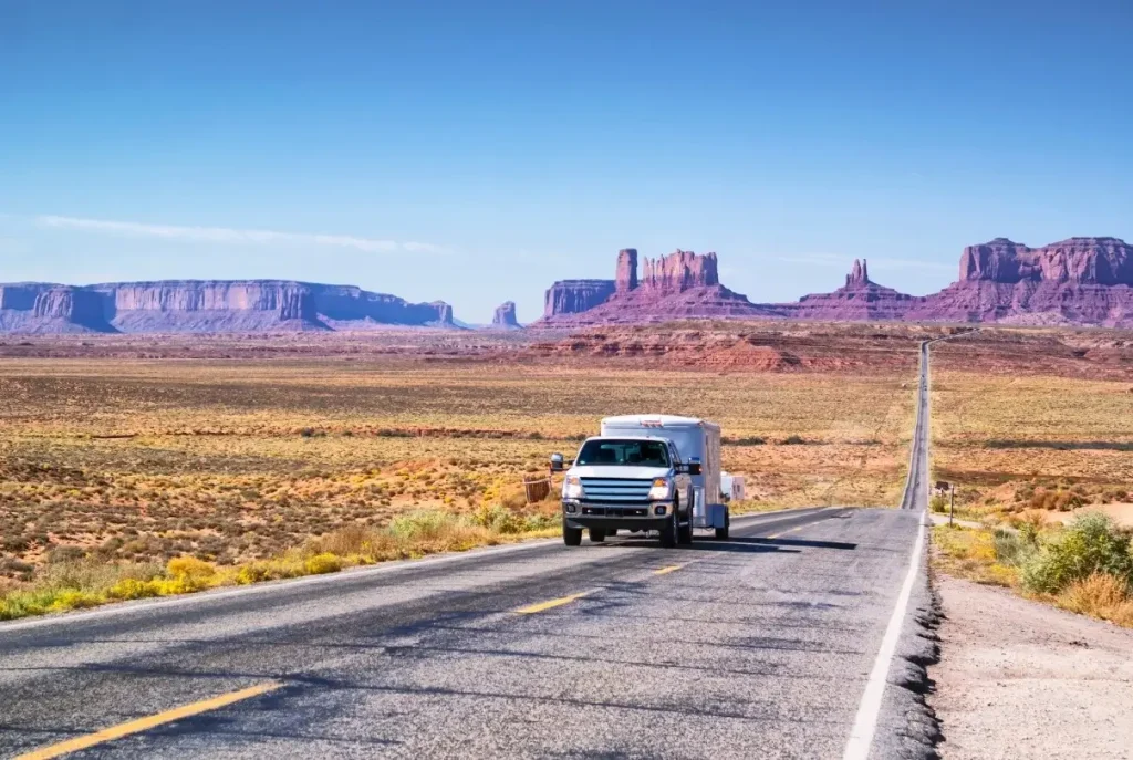 An SUV with a towable RV driving down an iconic highway in Arizona.