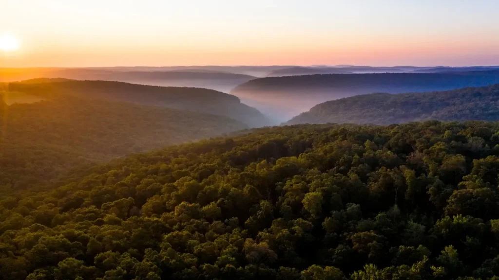 The Ozarks in Arkansas photographed at sunrise from a famous lookout with mist-covered mountains below.