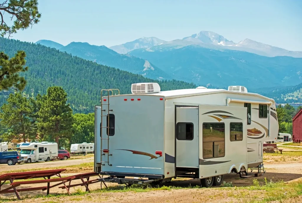 An Outdoors 5th wheel sits parked in a hard-to-reach campground surrounded by mountains, showcasing its superb off-road capabilities.