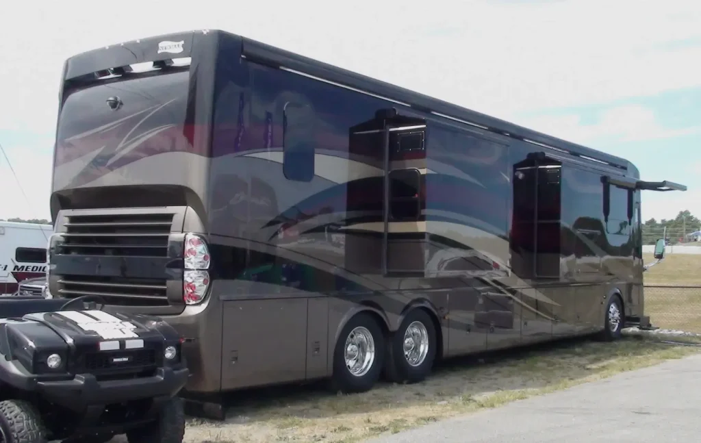 A luxury Newmar motorhome is parked in an RV lot with its slide-outs extended.