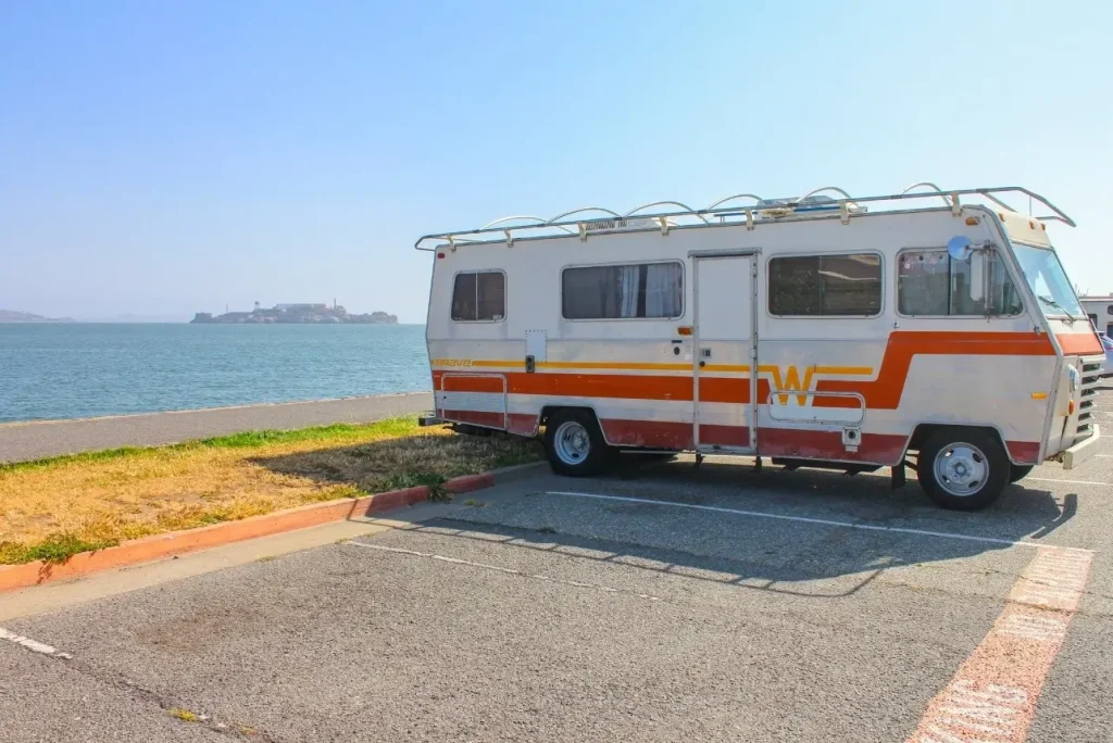 A classic reliable Winnebago RV is parked by the ocean. 