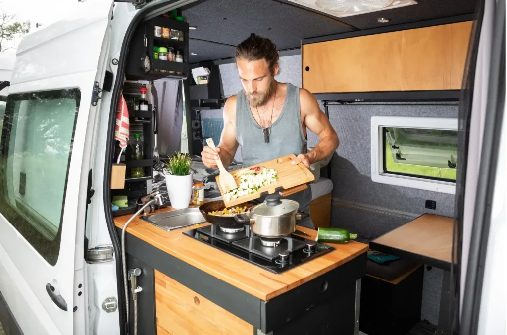 Man cooking breakfast in his converted camper van