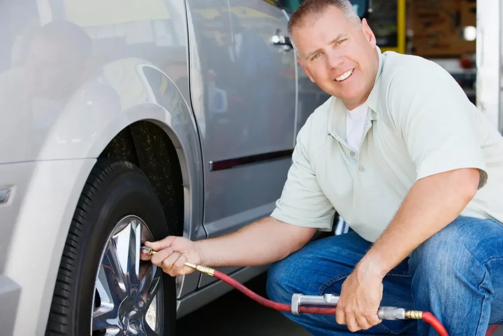 An RV owner checking his camper van tire pressure as part of a dewinterization checklist.