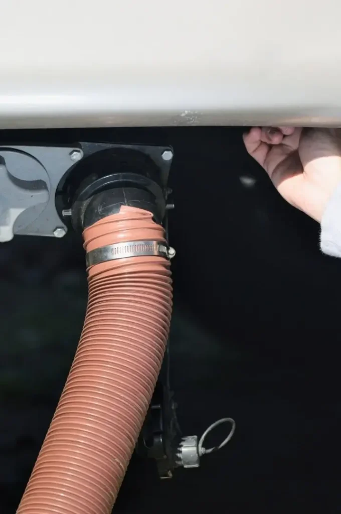 A black tank sewer hose being inspected by the RV's owner when conducting dewinterization mainteance on the rig's plumbing and water system.