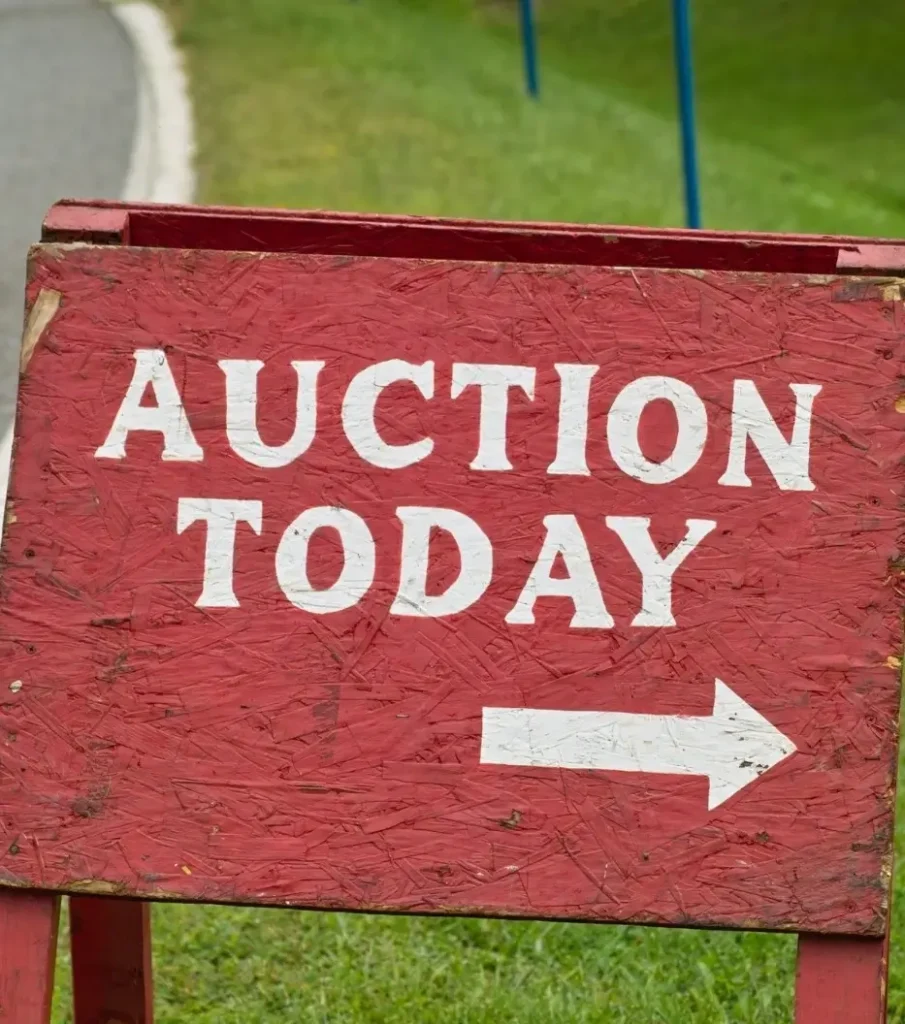 A red wooden sign with "Auction Today" painted in white and showing an arrow pointing to a nearby motorhome auction.