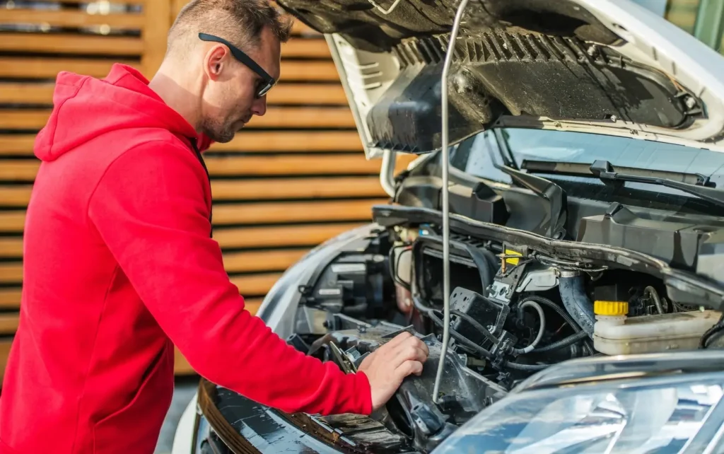 A mechanic inspects the engine of a camper van as part of a pre-purchase inspection during the sales process.